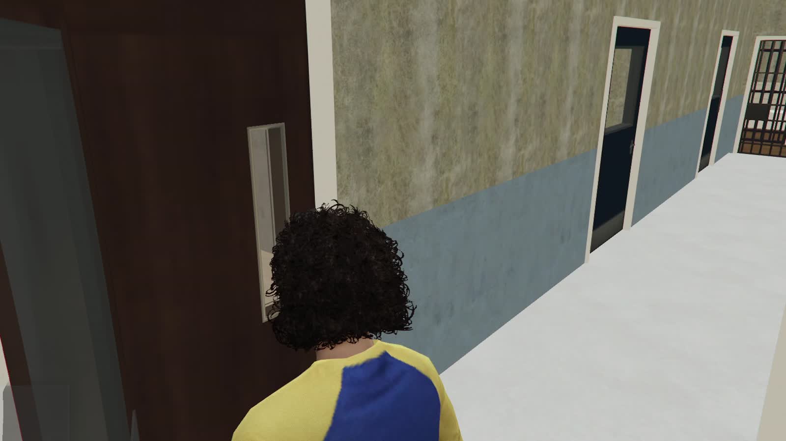 In game: the police station corridor with framed doors and a cell gate at the far end